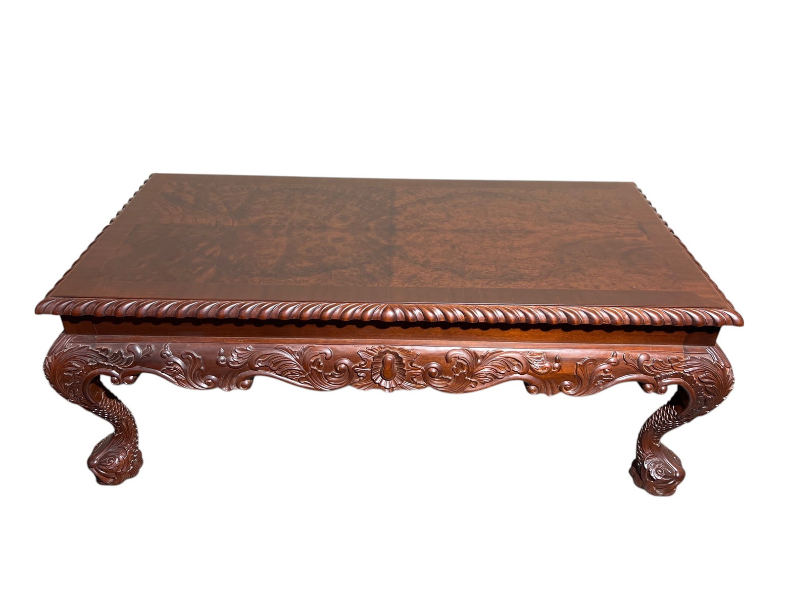 $3,500+ Carved Mahogany Coffee Table with Classical Ornamental Detailing: This exquisite coffee table showcases masterful craftsmanship in mahogany wood, featuring a richly carved apron with intricate scroll and floral motifs. The table’s striking borders present a twiste