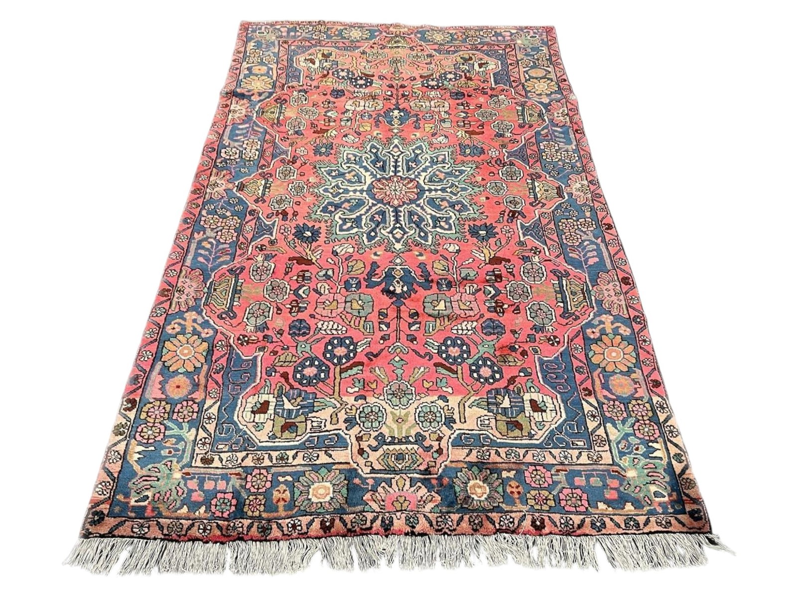 $3,910 - Coral Field Persian Nahavand Rug, Hand-Knotted Wool, 5'1" x 8'7": $3,910. A warm coral-rose field glows against a deep navy medallion at its heart, the ground scattered with sage, sky blue and ivory blossoms and closed by a navy border of linked sunburst rosettes. N