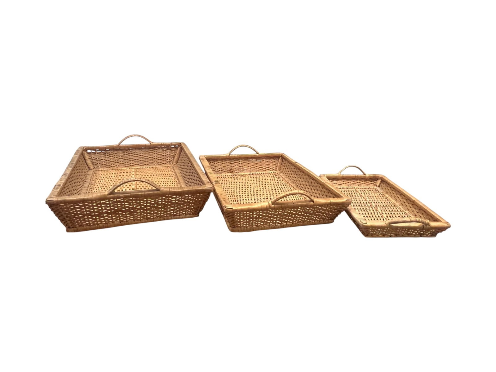 Trays Woven Rattan Graduated Serving Nest, 4": Set of three woven rattan trays in graduated rectangular forms, each fitted with integrated side handles and a warm natural finish. The group includes one large, one medium, and one shallow small