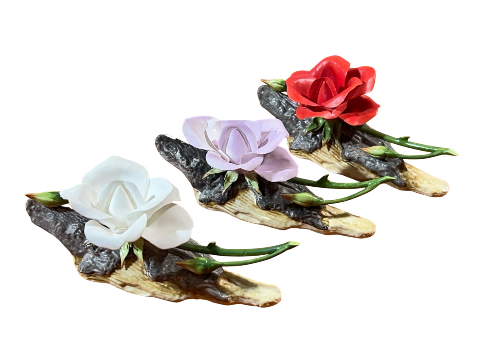 Boehm England Bone Porcelain Rose Sculptures, Set of Three, Made in England, 5" H: A refined set of three late-20th-century Boehm bone-porcelain floral sculptures, Made in England, each modeled as a single rose in bloom resting across a naturalistic faux-driftwood base. Each piece p