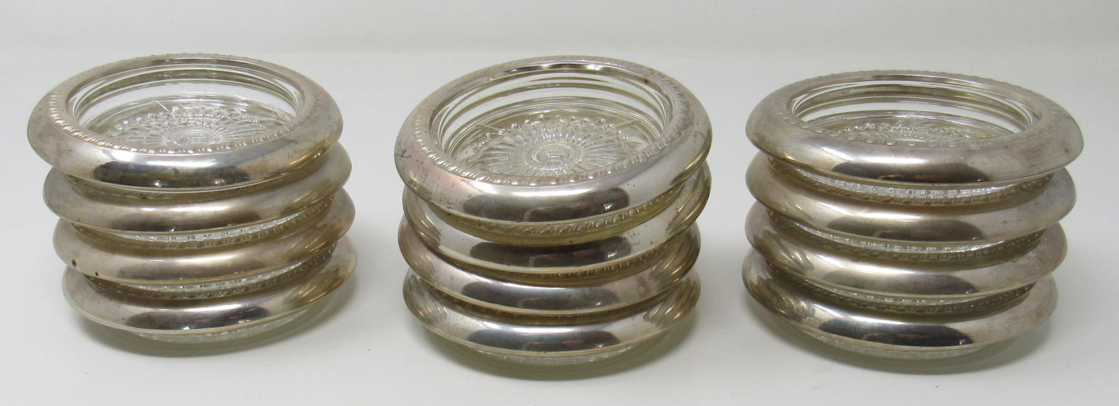 12 Coasters with Sterling Silver Band: Approx 4" in diameter. Marked Sterling