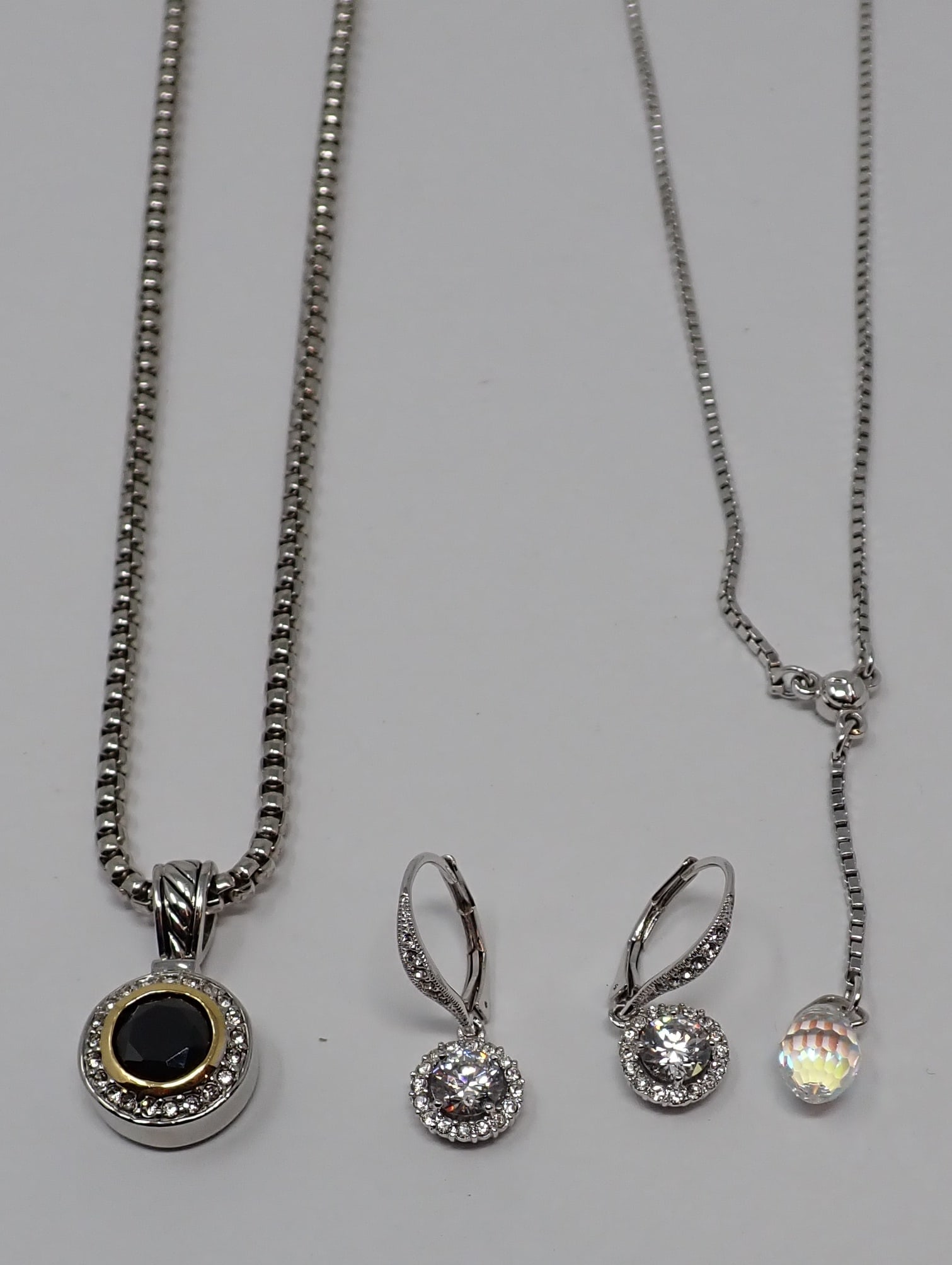Costume Necklaces and Earrings: Includes a silver-tone Swarovski chain with crystal drop, metal Swarovski tag; a pair of silver-tone rhinestone drop earrings; and silvertone snake link chin supporting a rhinestone pendant.