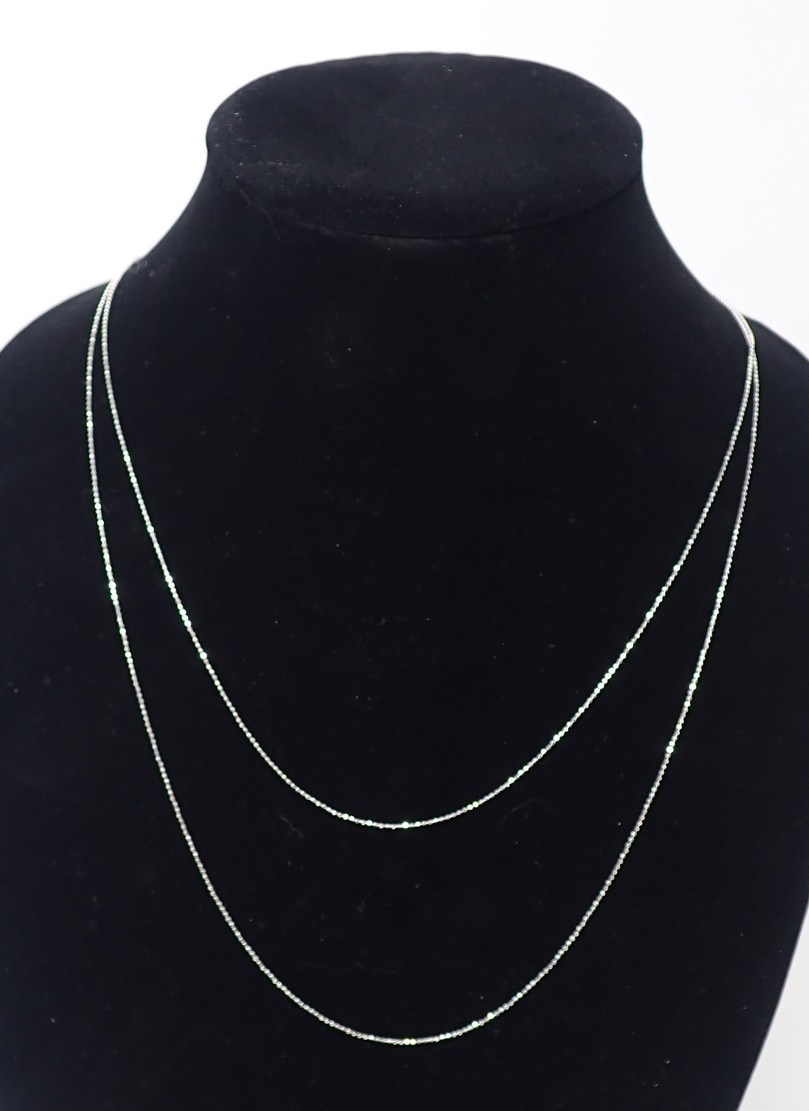 2 White Gold Necklaces: Pair of matching 24" faceted bead chains, 2.44 dwt total.