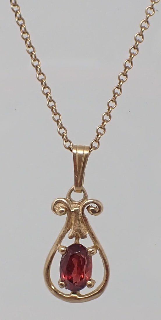 Gold and Garnet Pendant on Chain: 14K yellow gold 16" chain supporting a petite 14K yellow gold pendant centered with an oval cut garnet, 1.51 dwt.