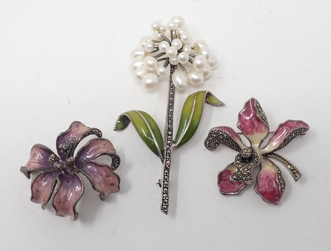 3 Sterling, Marcasite and Enameled Floral Brooches: Including two of flower blooms and one with stem, leaves and scattered cluster of pearls as the bloom, 1.81 ozt total.
