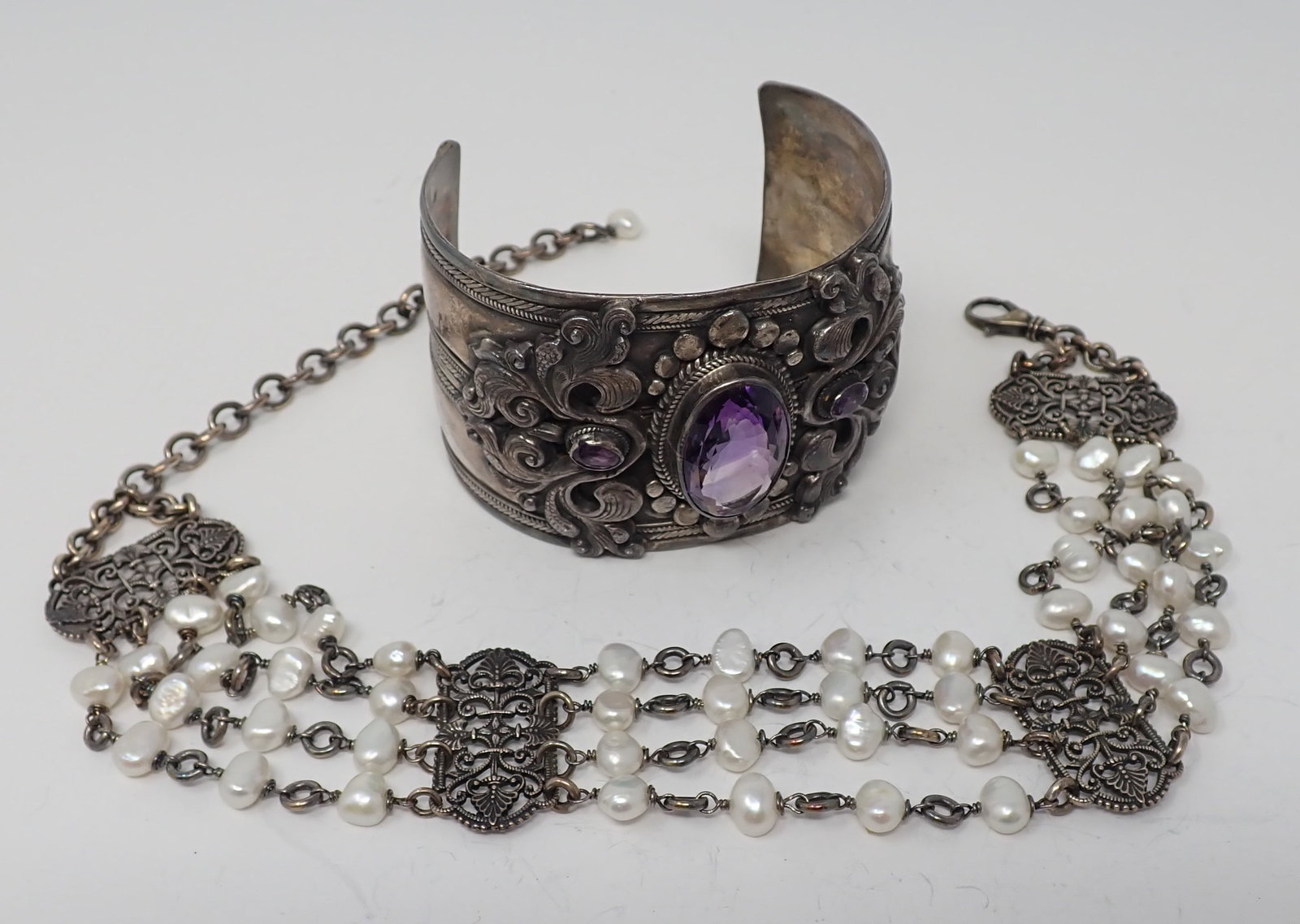 Silver Cuff and Choker: Complementing group. Approx. 2" wide cuff with ornate applications,centered with a large oval fancy cut amethyst; along with an ornate silver and pearl choker. 3.62 ozt total.