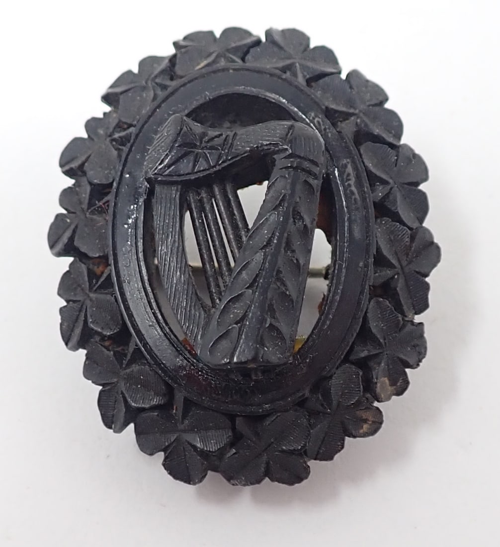Victorian Carved Jet Brooch: Irish themed with a center harp surrounded by clovers, approx. 1.5" tall x 1.25" wide.