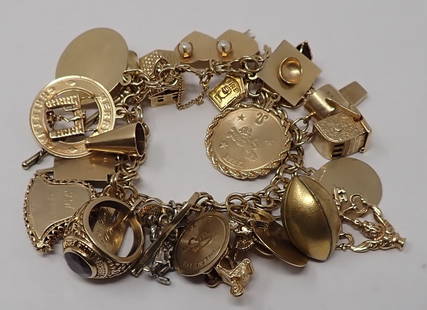 Gold Charm Bracelet: 14K yellow gold double curb link bracelet supporting approx. 29 charms, at least 25 are 14K yellow gold, one 10K school ring, and others. 64.87 dwt.