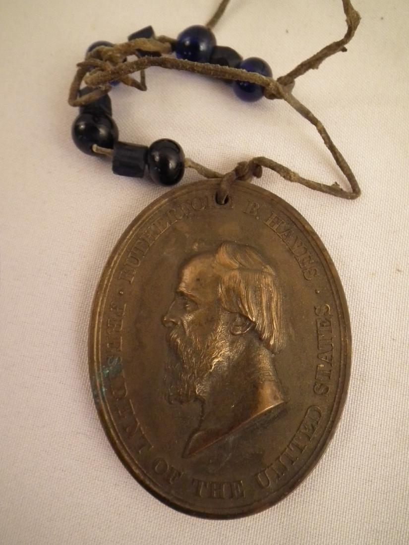INDIAN PEACE MEDAL HAYES: American Indian oval bronze peace medal with President Rutherford B Hayes - blue glass trade beads attached. 3 inches x 2.32 inches.