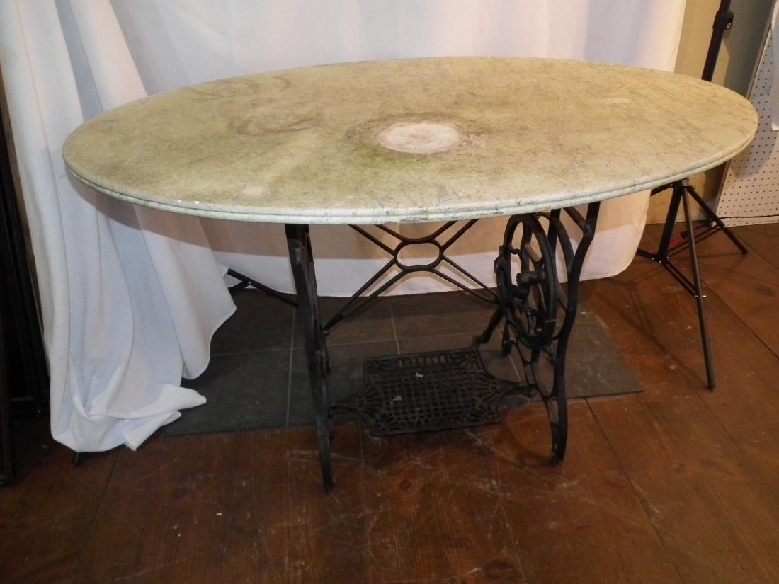 MARBLE TOP SEWING TABLE: Large antique oval marble top table with antique iron sewing machine base (was used outdoors). Marble worn/discolored. Top is 47 x 30, 30 in high.