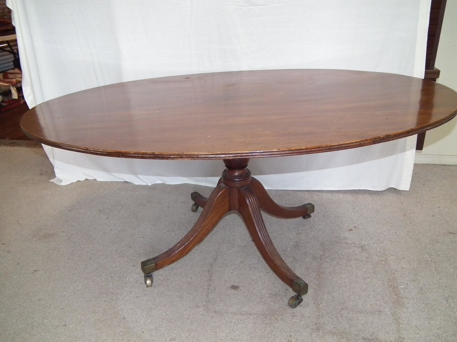 HUGE TILT TOP BREAKFAST TABLE: Large antique English tilt top breakfast table with oval 65 in x 47 inch top (one piece of wood!). Splayed leg base with brass caps. Circa mid 1800's.