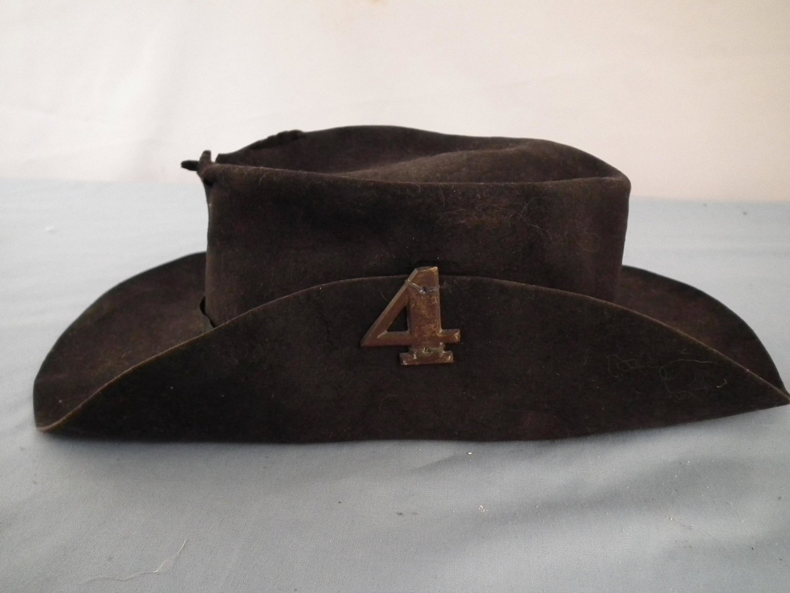 CONFEDERATE FELT HAT: Rare Civil War Confederate black felt hat with number 4 brass corps badge. Interior has leather sweat band with very light pencil id --JWN 1861 Co. F. About 12.5 in long. Has hold on top edge. VA esta
