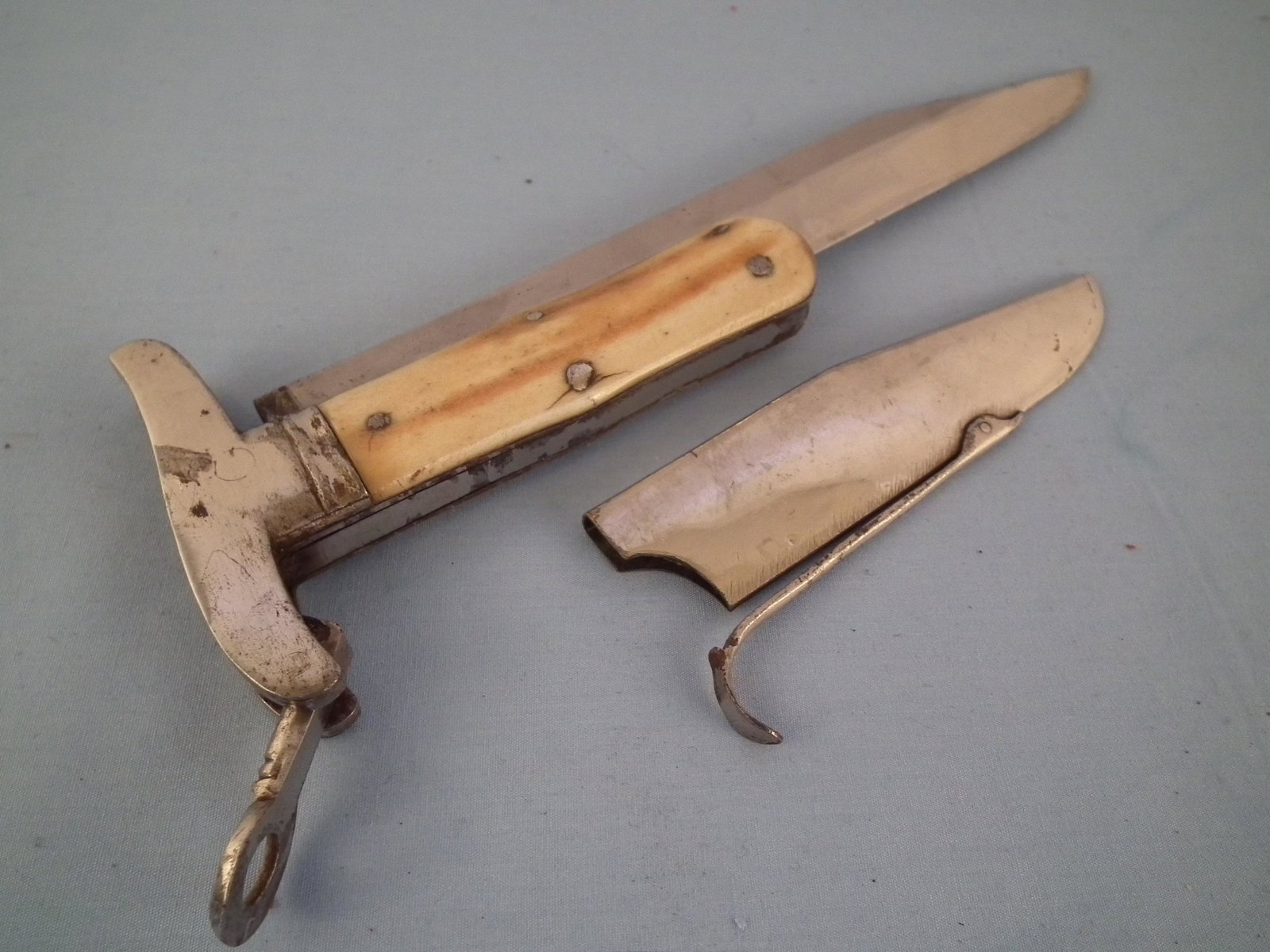 RARE FOLDING KNIFE: Unusual antique folding knife with silver plated clip-on sheath, bone handle, 8.25 in blade having stippled flowers signed ECW. 13 in overall.
