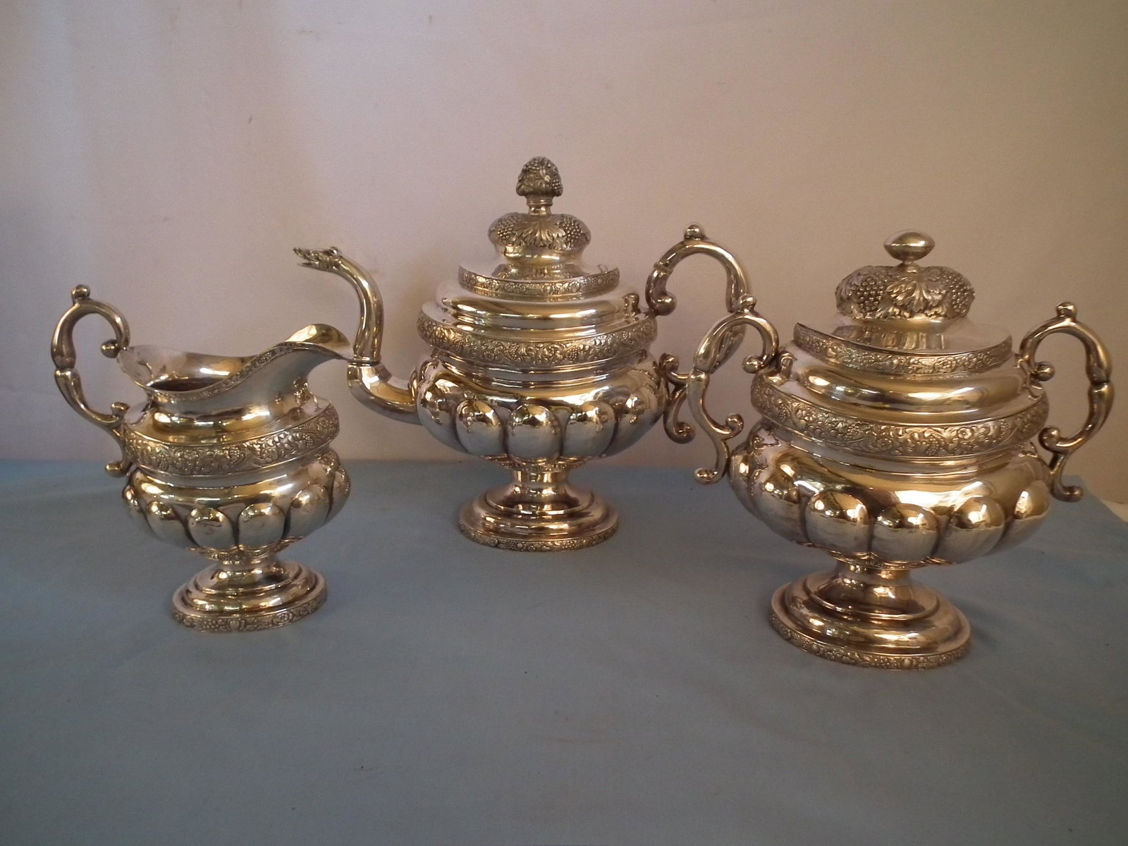 ANTIQUE COIN SILVER TEA SET: Oversized antique coin silver teapot, covered sugar, and cream pitcher signed J. CRAWFORD with fancy repousse designs. Pot is 10 x 12 inches, creamer 7.5, and sugar 9.5 inches. Totalwieght 58.2 ozt.