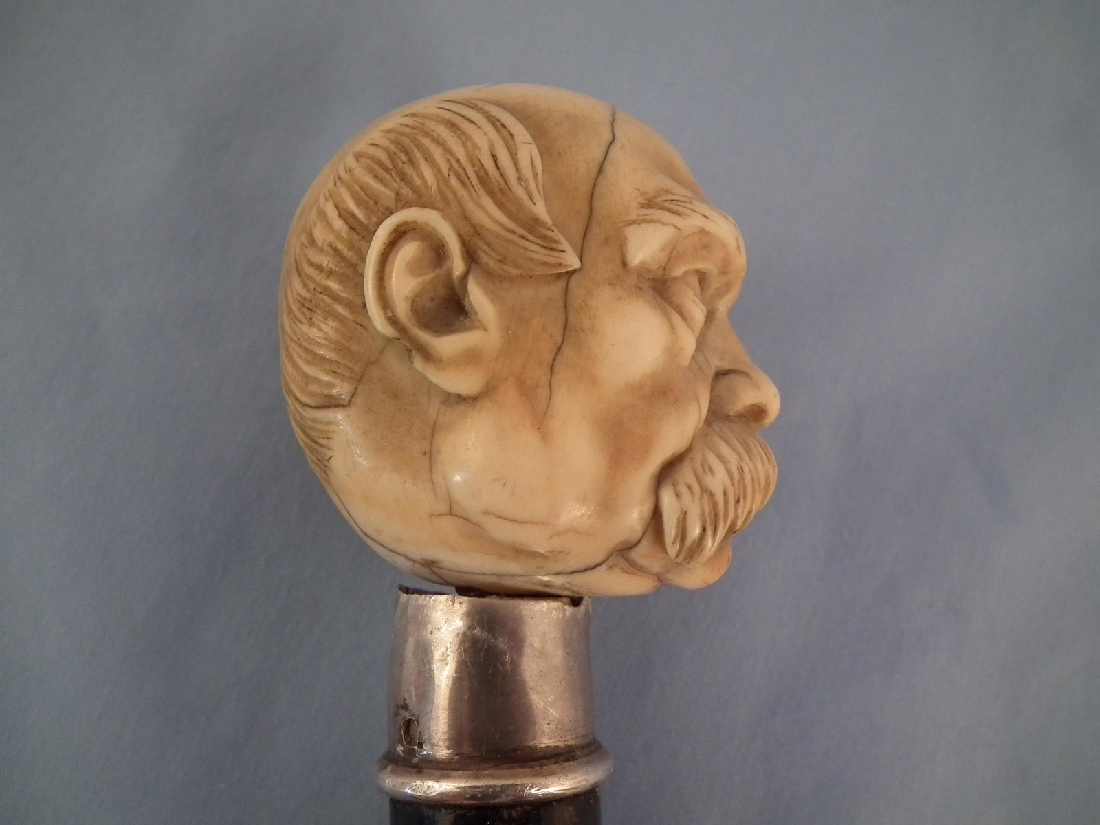 ANTIQUE GROVER CLEVELAND CANE: 19th century carved bone cane with bust of a balding man with mustache (crack) believed to be President Grover Cleveland, stamped 925 silver collar, ebony shaft and bone ferrule. 35 in long.