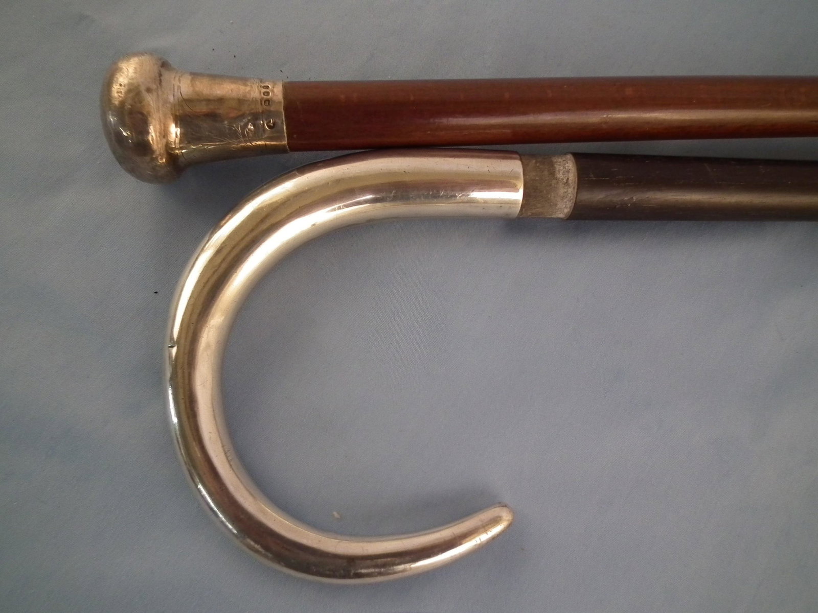 2 OLD SILVER CANES: Lot of 2 old silver canes with wood shafts: shepherd's hook with engraved FBM initials, 33.5 inches; and engraved knob handle with English sterling hallmarks, 36 in long.