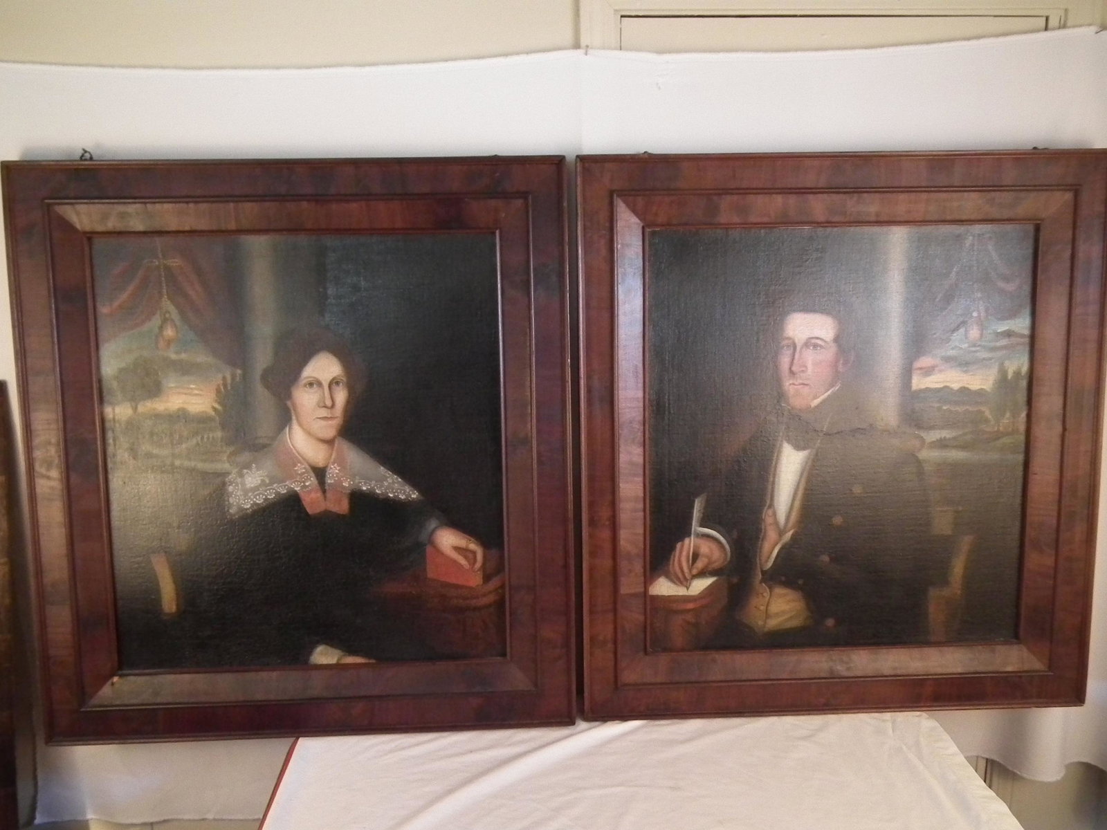 ES FIELD FOLK ART PORTRAITS: A fine pair of mid 19th century folk art oil on canvas portraits - Man writing with quill by an open window; and woman holding book by open window. Unsigned, attributed to Erastus Salisbury Field. Bot