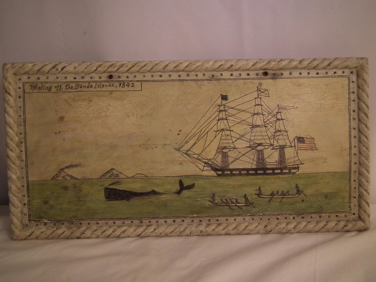 OLD PLAQUE PAINTED WHALING SCENE: Old hand painted wood plaque WHALING OFF THE BANDA ISLANDS 1842. Whaling scene with whale ship GULL, a black whale and whaleboats. Rope edge, 10 x 21 inches.