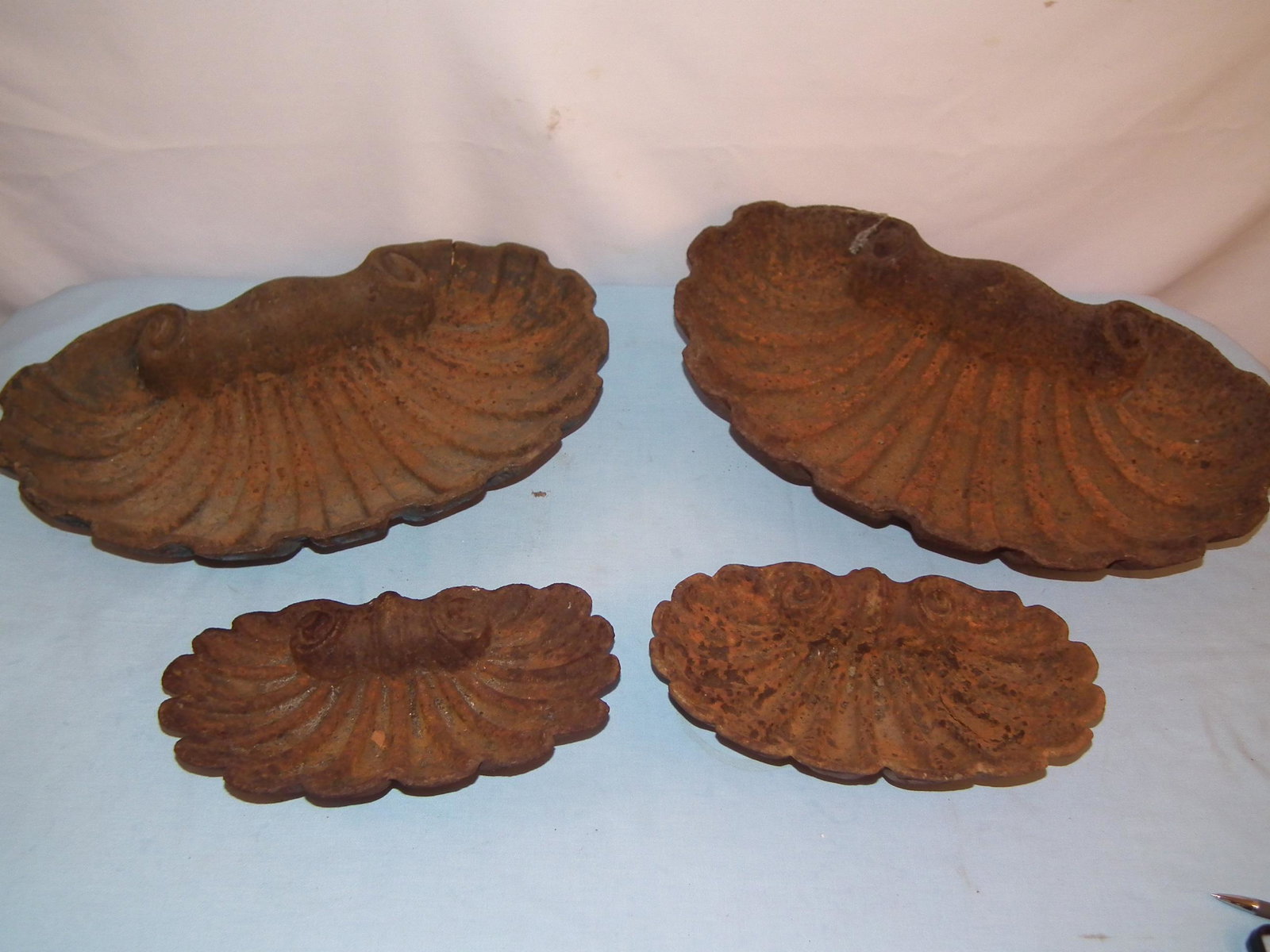 4 ANTIQUE IRON GARDEN SHELLS: Lot of 4 old iron garden ornaments in the form of sea shells (bird bath/fountain?), from 13 to 21 inches diameter. Rusty surface.