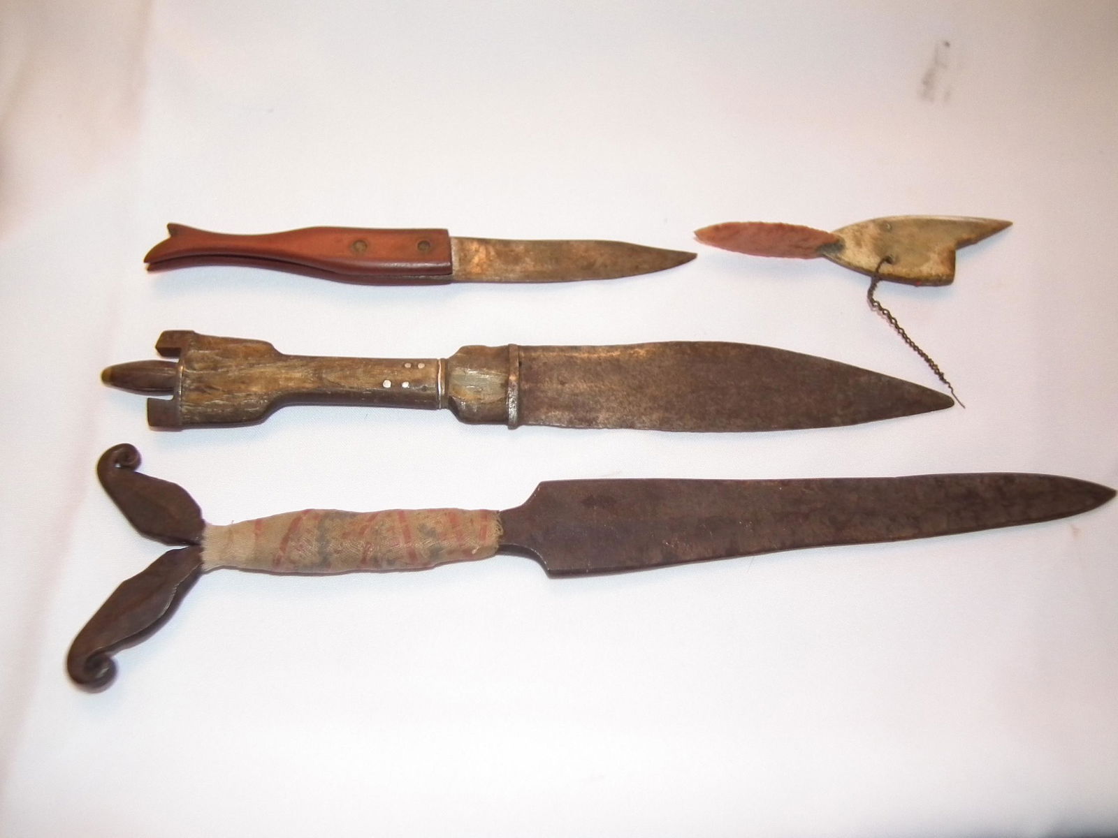 3 NATIVE AMERICAN KNIVES: Lot of 4 items: 6 inch bone and carved stone Native American spearhead with fish design; 15 inch iron knife with scrolled ends, possibly Tlingit; 13 inch Native American wood and metal knife with shap