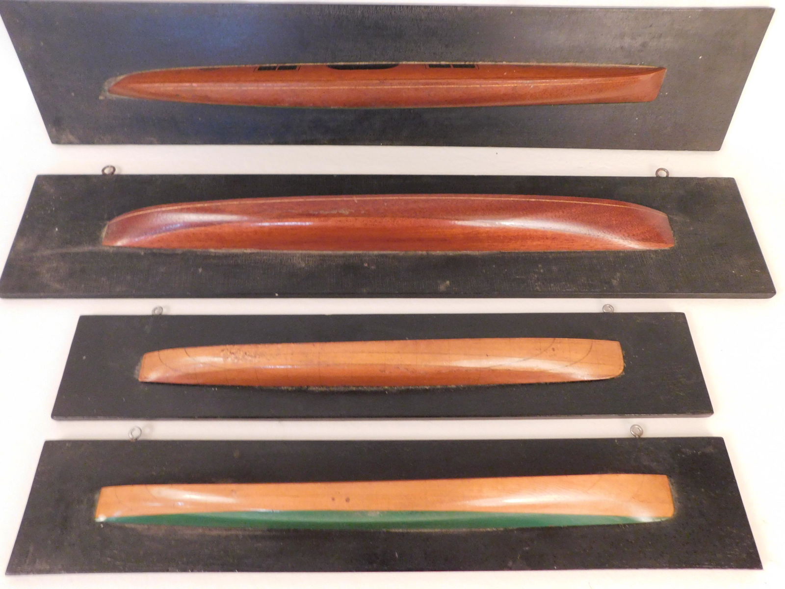 SET 4 HALF HULL MODELS: Group of 4 old, narrow half-hull painted ship models from 16 to 21 inches long, mounted on black backboards. Two have design lines and markings.