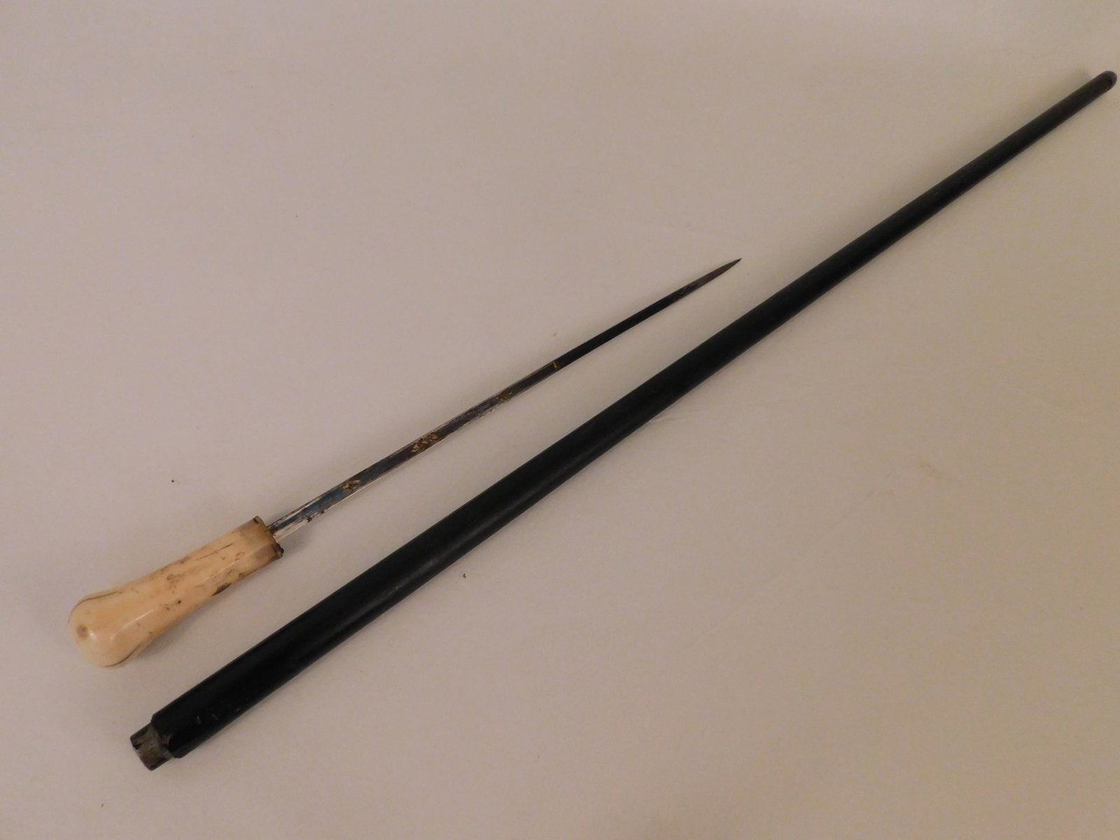 ANTIQUE SWORD CANE: Antique sword or dagger cane with 3 inch high bone knob, 12 inch long short sword with gilt decoration, wood shaft. 34 in long. Some imperfections to handle.