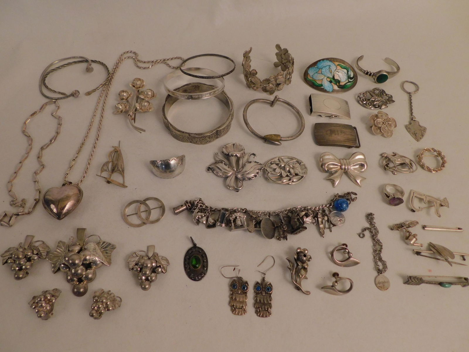 LOT OF STERLING SILVER JEWELRY: Assorted lot of sterling silver jewelry including: bracelets; brooches; 2 buckles; charm bracelet; 5 pc Mexican grapes suite; 2.75 in enamel brooch; necklaces; earrings; and 1983 Cummings wide bracele