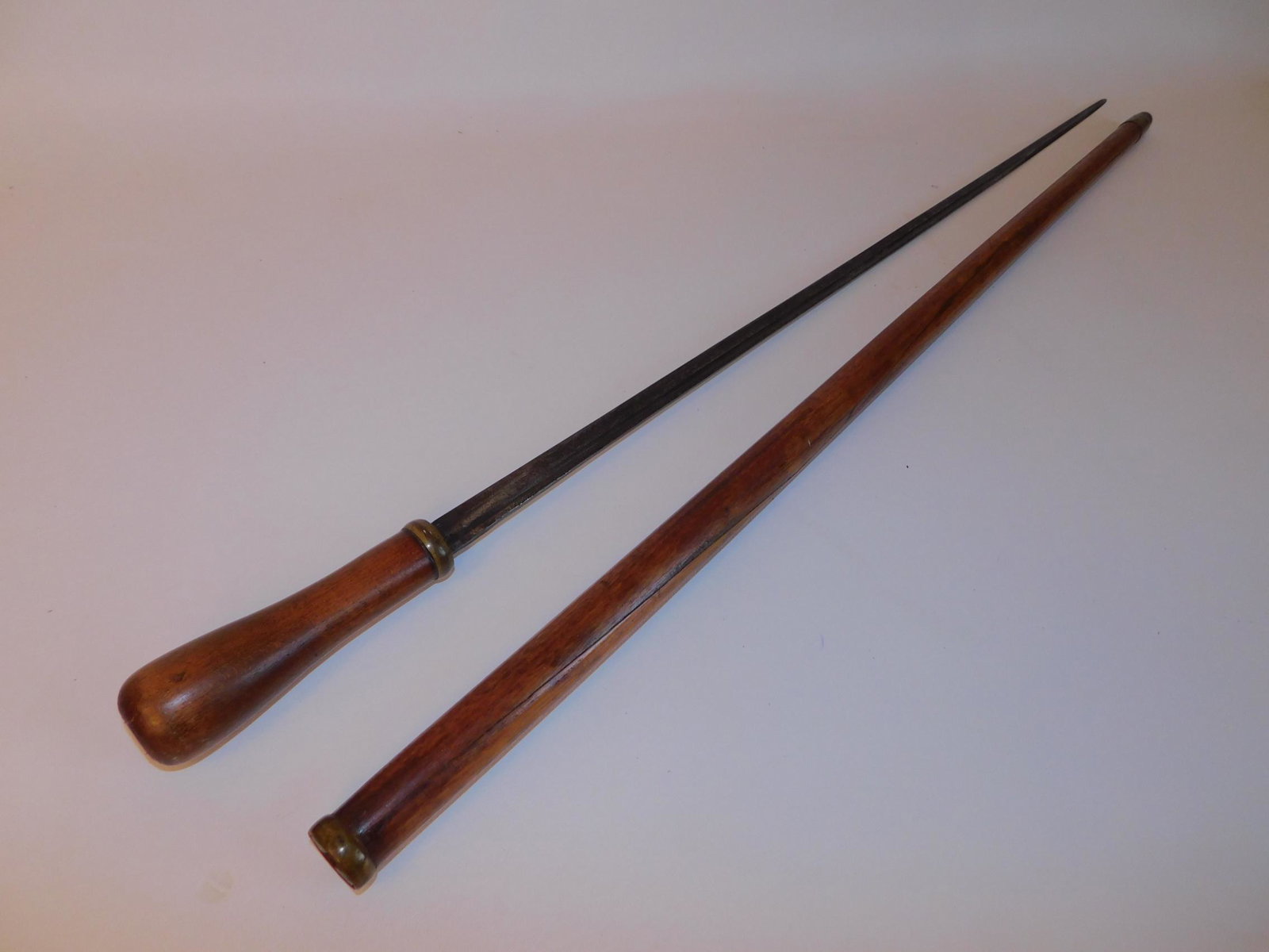 ANTIQUE SWORD CANE: 19th century sword cane with wood scabbard and handle. Blade is 28 in long, overall 35.25 inches.