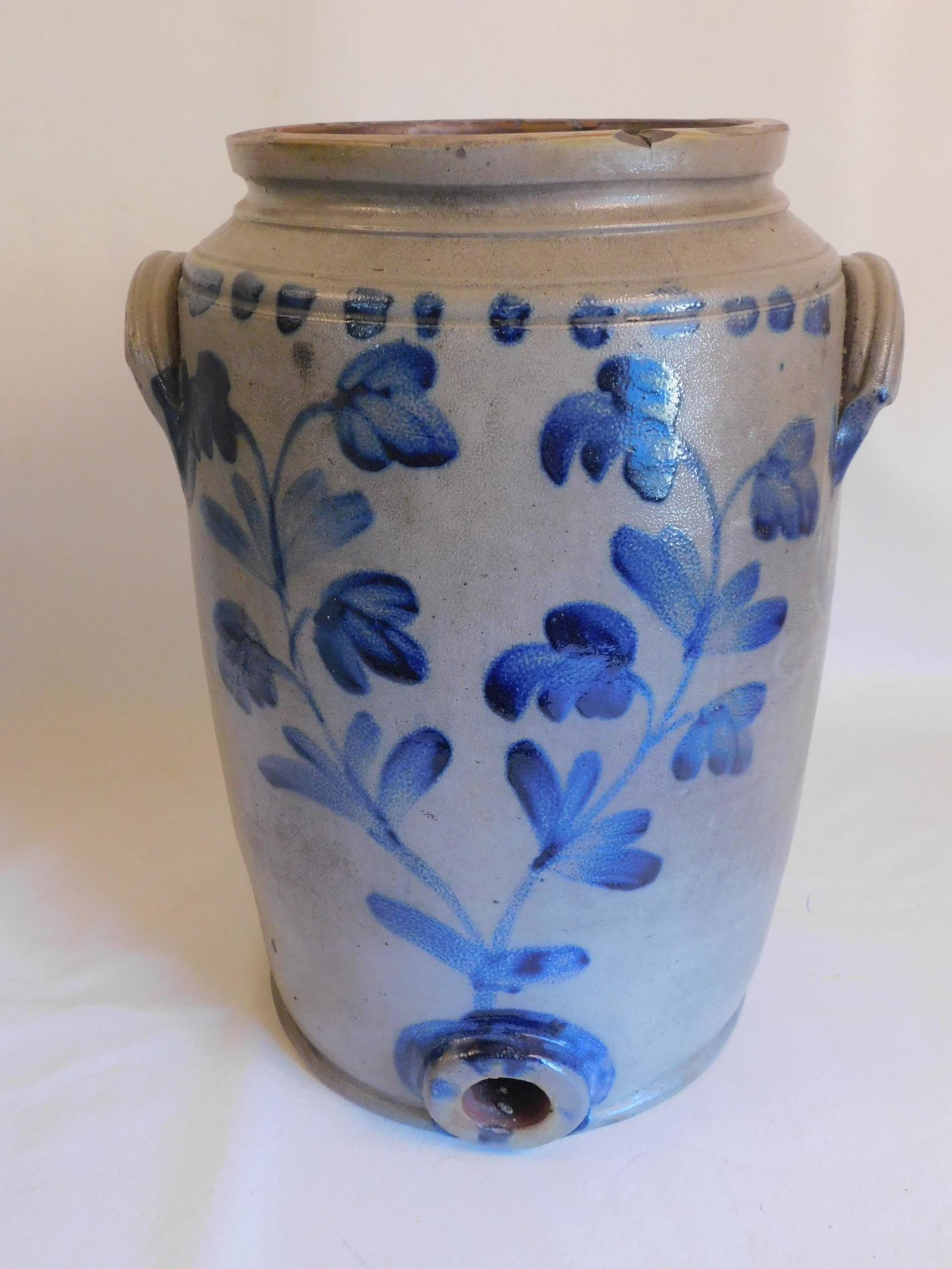 PENN. STONEWARE WATER COOLER JUG #4: Antique stoneware water cooler jug with spigot from Pennsylvania having floral decoration on both sides, #4 stamp, 16 in tall. Small chips and couple hairline cracks on top rim. Unsigned.