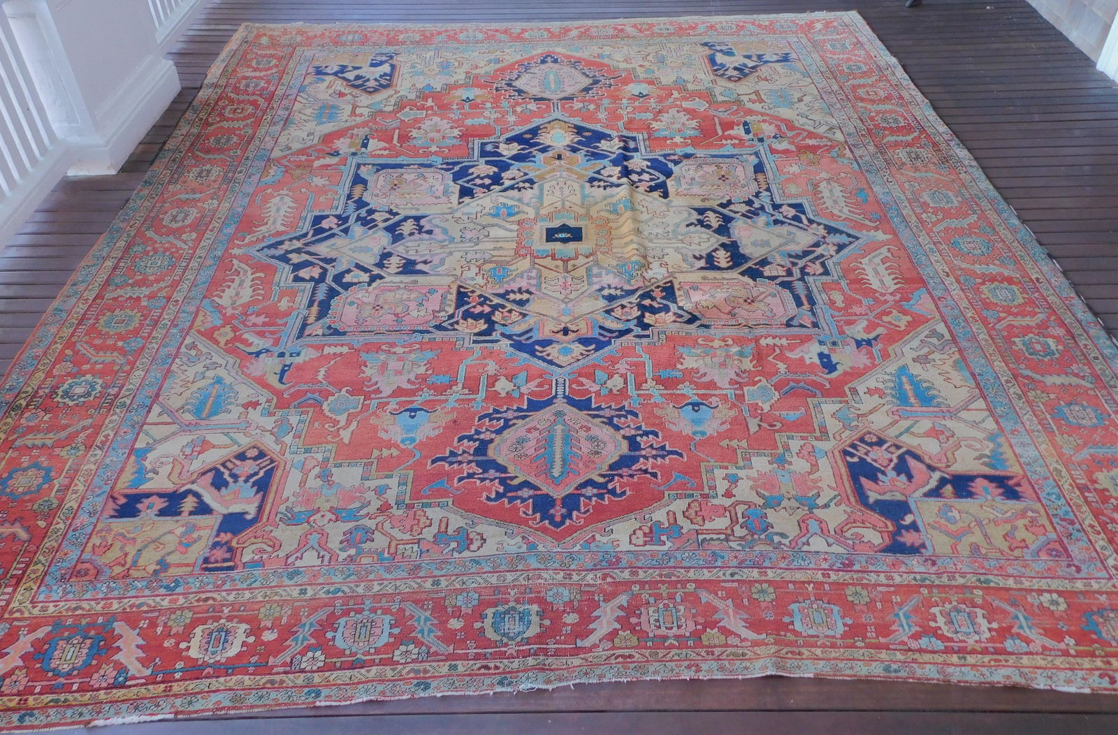 ANTIQUE PERSIAN SERAPI HERIZ CARPET: Antique Persian Heriz Serapi / Heriz room size carpet with rust colors and geometric designs circa 1920. 11 feet by 13 ft 4 inches. Has small hole in center medallion for call button. VG overall condi