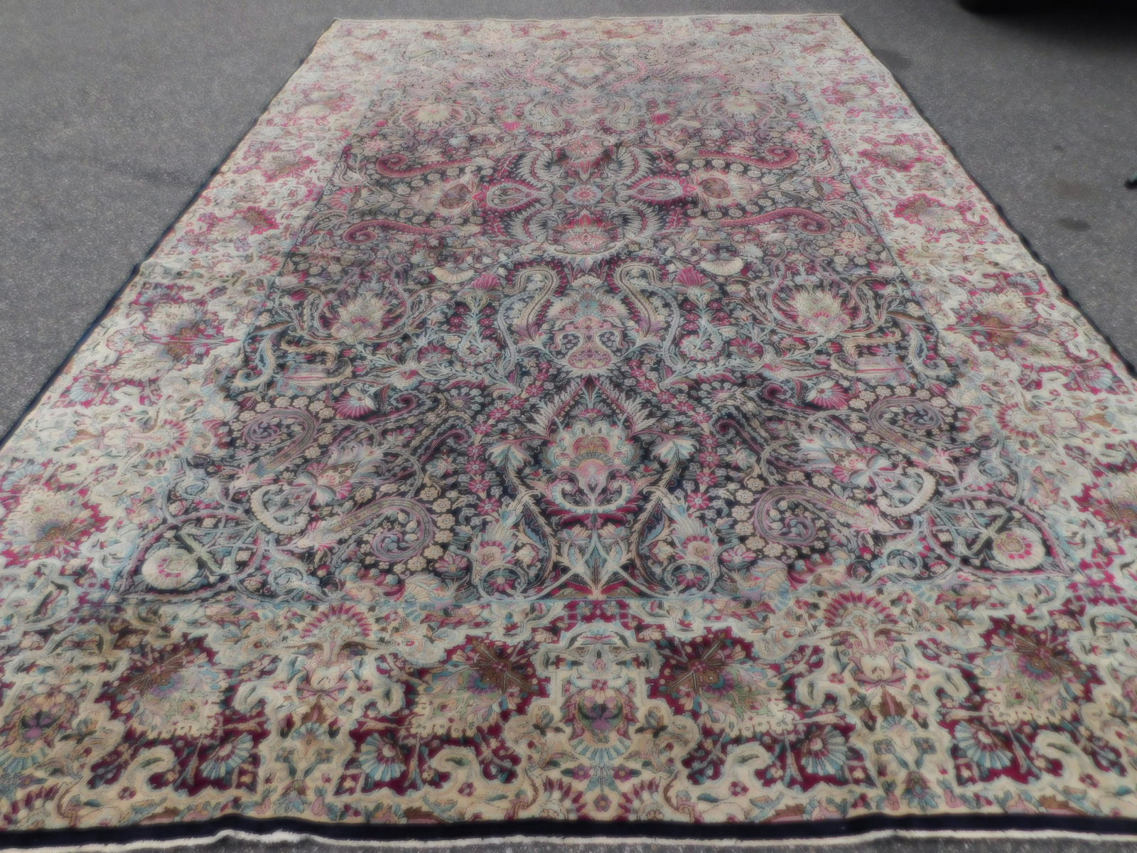 ANTIQUE KIRMAN 15 FT. CARPET: Fine semi-antique Persian Kirman carpet with navy blue ground and elaborate flowering designs. 9 ft 10 inches by 15 ft 4 inches. Some scattered wear.