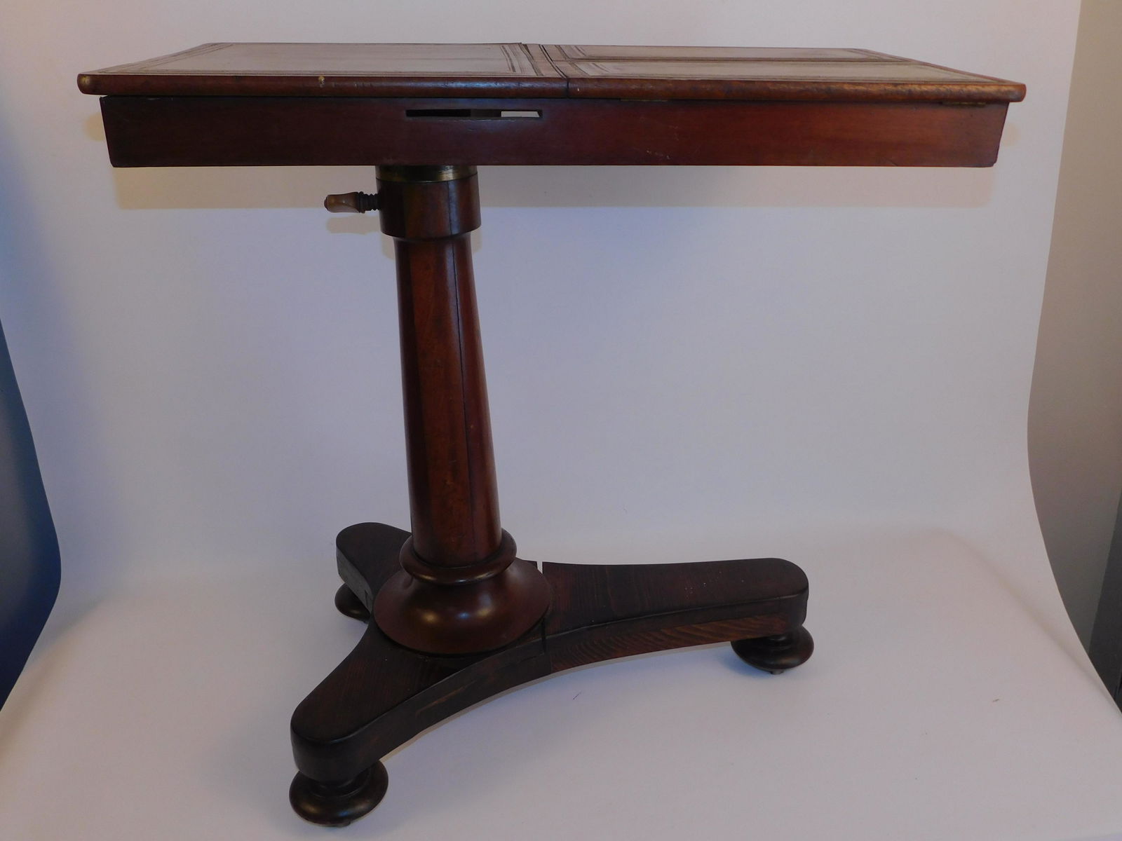 ANTIQUE REGENCY MAHOGANY GAME TABLE: 19th century mahogany Regency game table with leather top and double folding and adjustable surfaces. Pedestal base will telescope for various heights. Some veneer loss on side. 28 in high x 28 x 12 i