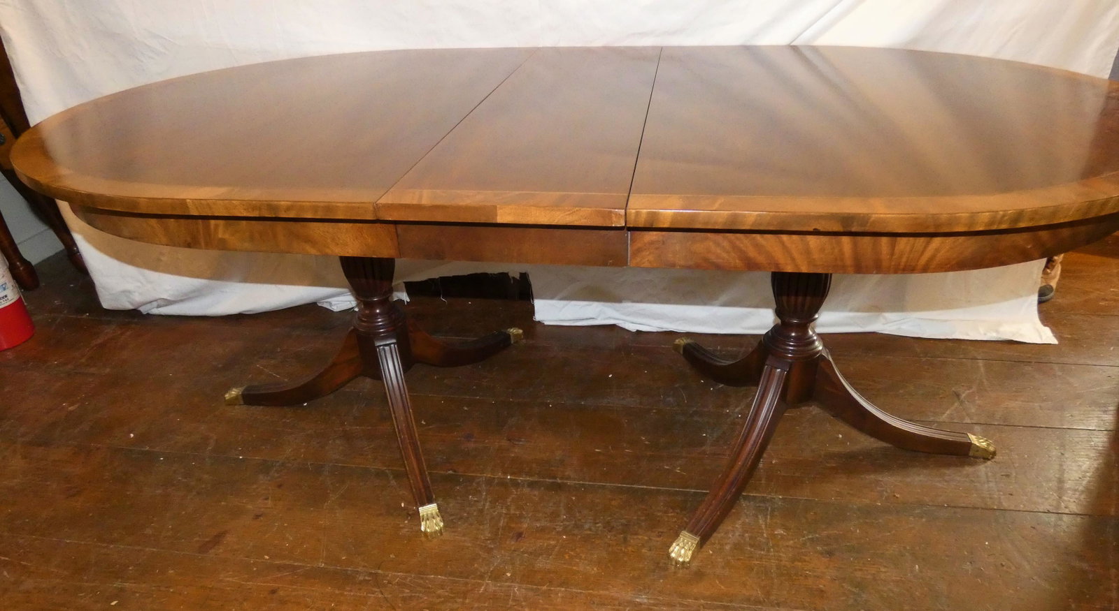MAHOGANY BANDED DINING TABLE: Fine custom mahogany oval dining table with double pedestal legs, brass paw feet and banded edge. Comes with four 12 inch leaves. Size (closed) 66 x 44 inches, 30 in high. Total length with leaves = 1