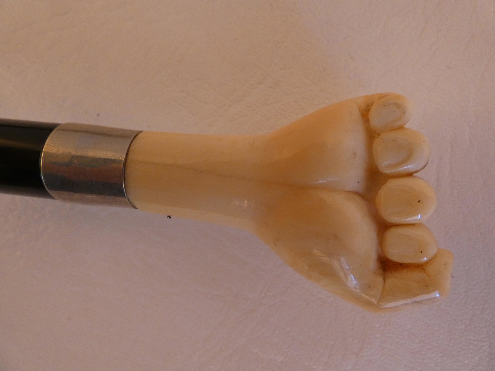 ANTIQUE BONE CLENCHED FIST CANE: Antique cane with carved bone clenched fist and silver collar, ebony shaft, 35 in long.