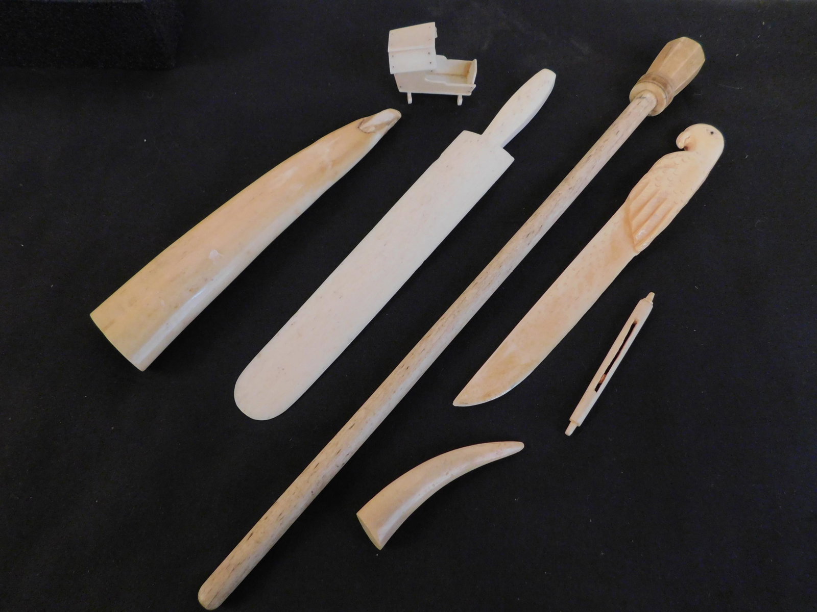 7 ANTIQUE WHALE BONE ITEMS: 19th century items include: parrot letter opener; 13 inch pointer or conductor wand; 6.25 and 2.5 inch whale teeth; miniature cradle, 1.5 in long; and 8.5 inch flat letter opener.