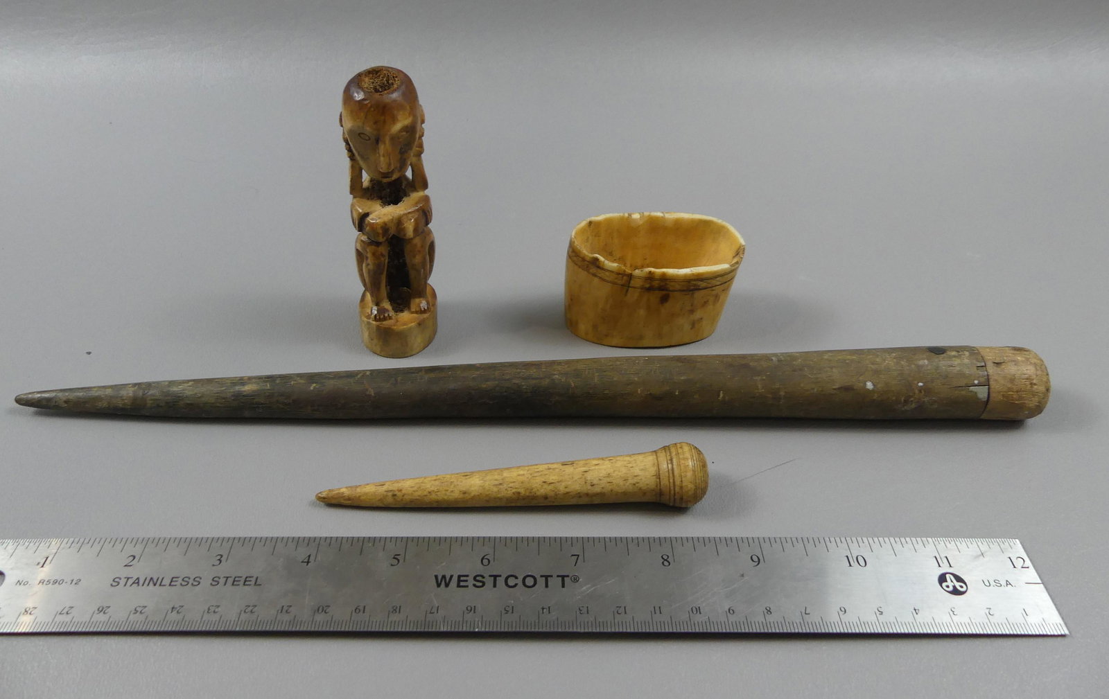 4 ANTIQUE BONE ITEMS: Lot including 13 inch long sail needle, 4.5 in needle, 4 inch African bone figure, and scrimshaw bone with geometric designs.