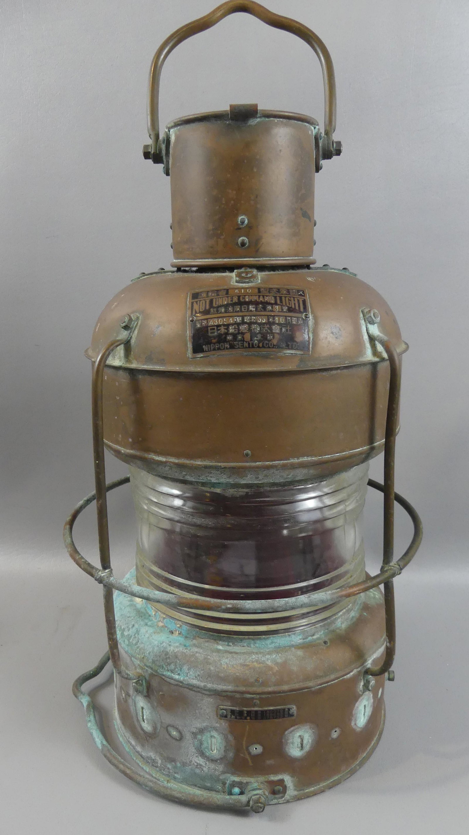 OLD JAPANESE BRASS SHIPS LANTERN: Old copper ship's lantern NOT UNDER COMMAND by Nippon Sento Co. Japan #510. Has clear glass lens and red chimney. 19 in high. Surface has some green corrosion.