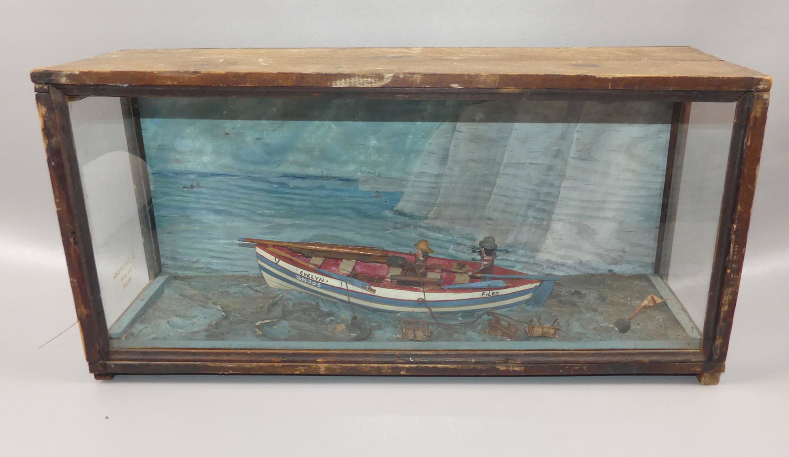 1932 SHADOW BOX SHIP MODEL: Folk art shadowbox wood and glass cased model of 2 men fishing in boat named the Evelyn Filey SH303 with painted background. Case signed S. Johnson Filey 1932. 24 x 12 x 8 inches.