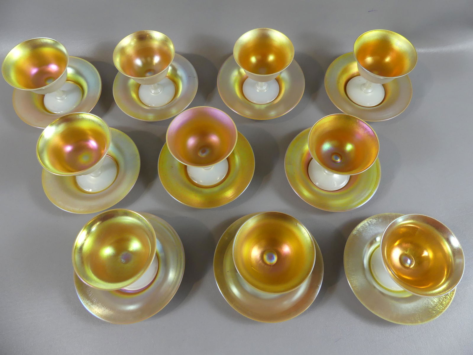 10 STEUBEN ART GLASS SHERBETS: Set of 10 antique Steuben art glass sherbet cups with underplates in gold aurene and calcite. All are perfect, cups are 4 x 4 inches, plates 6 in diameter. Cups have polished pontils.