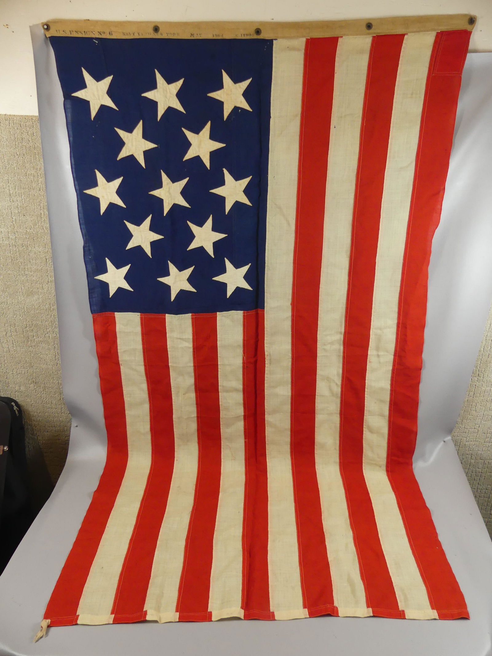 1904 NAVY ENSIGN 13 STAR FLAG: Antique American 13 star ensign flag stencilled on end US ENSIGN NO. 6 NAVY YARD NEW YORK, MAY 1904 C11903. Brass grommets stamped with patent date 1884. Size: 77 in long x 43 high. VG/EXC condition w