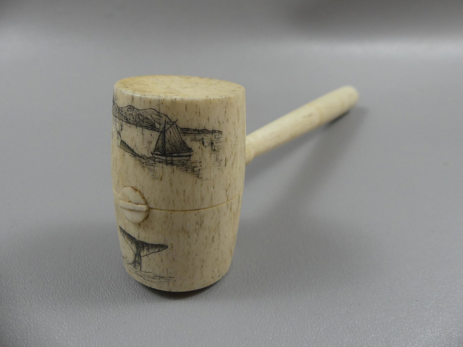 ANTIQUE WHALE BONE GAVEL WITH SCRIMSHAW: A fine 19th century whalebone sailor-made gavel with scrimshaw scenes on terminal depicting a whale's tail and seascape with sailboat and whale. Size: 9.5 in long x 2.5 x 1.5 in diameter. VG condition