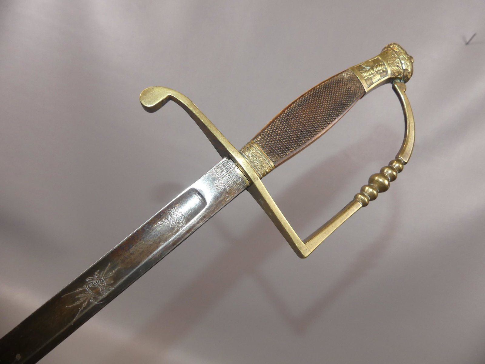 EARLY FRENCH ENGRAVED SWORD: Circa 1800 officer's sword with five-ball hand guard attributed French, with brass pommel having embossed eagle holding lightning bolts and carved bone grip. 33 in long engraved blade (maker initial D