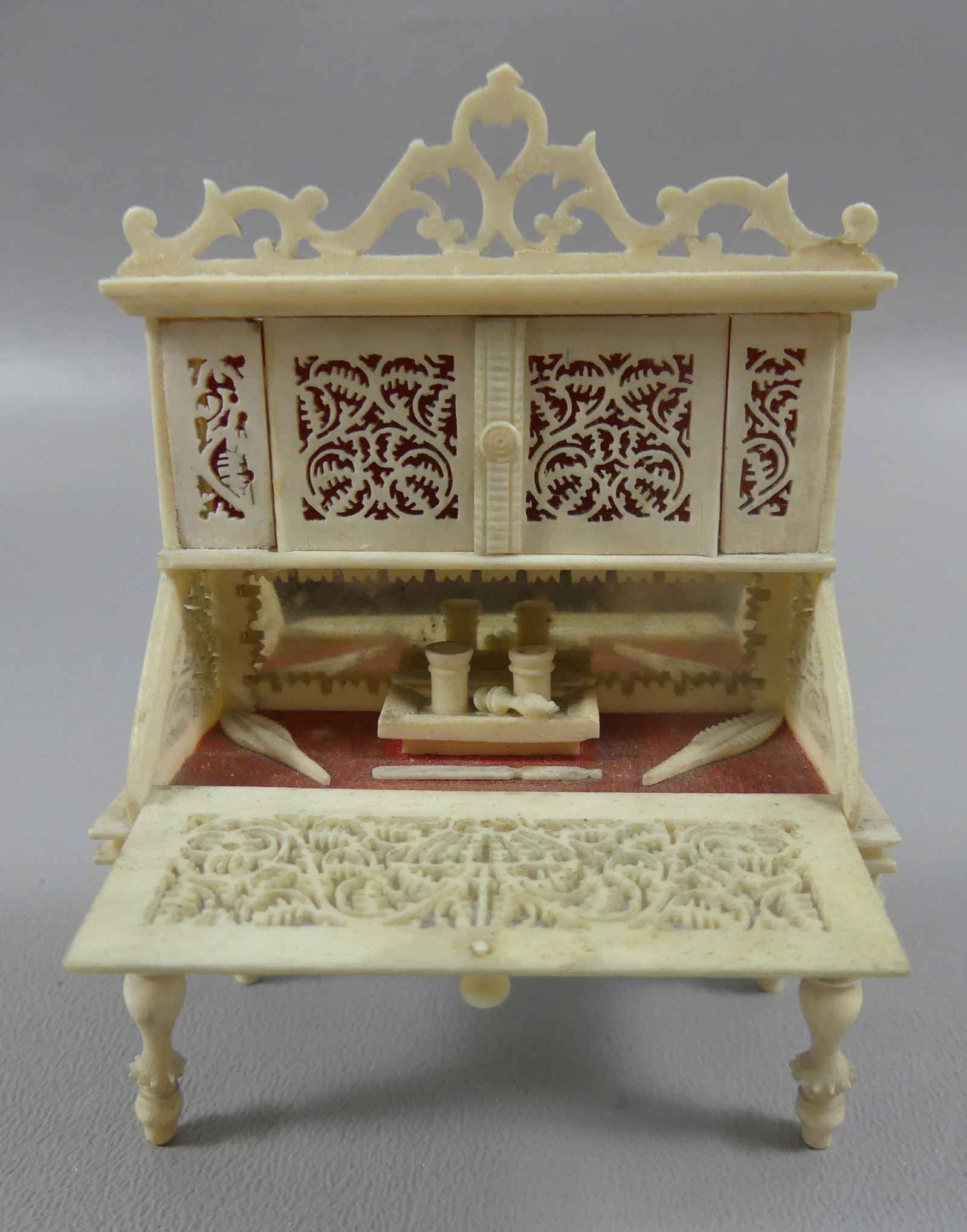 CARVED BONE MINIATURE SECRETARY DESK: Rare carved bone miniature secretary desk with mirror and interior writing implements. Pierce-carved upper doors and side panels. 3.5 x 2.5 x 1.25 inches. VG cond.