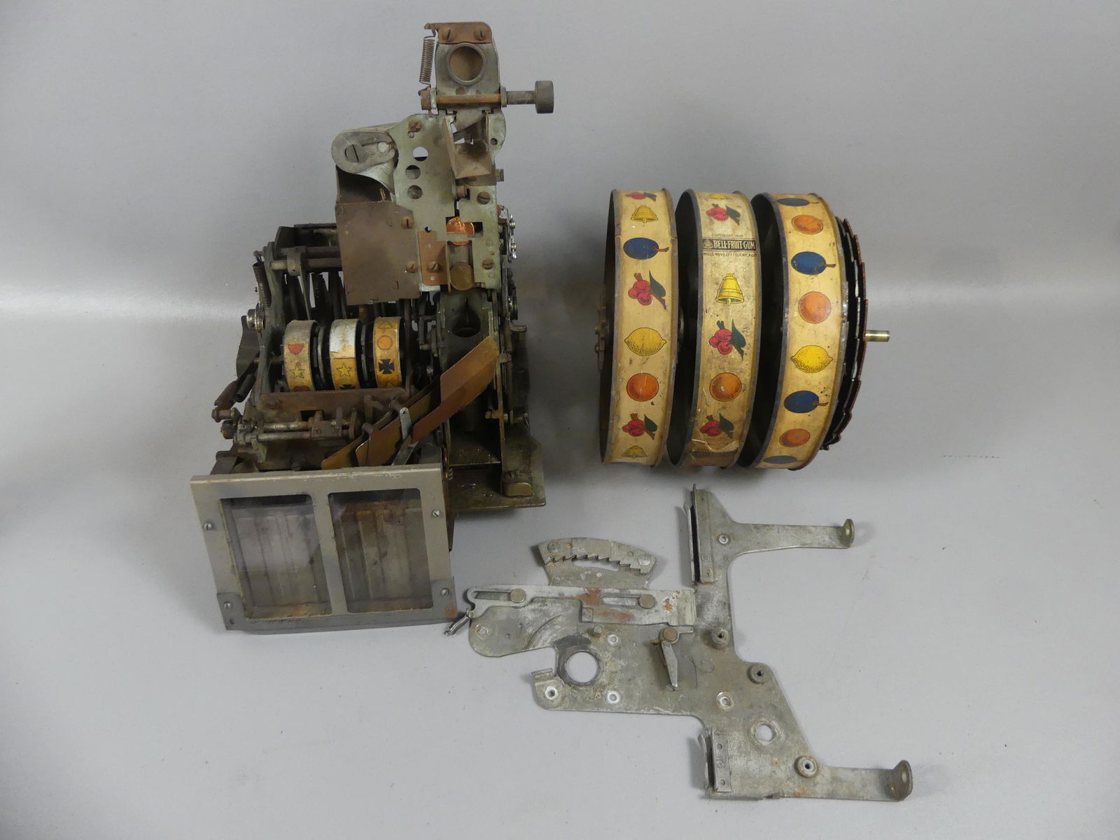 ANTIQUE SLOT MACHINE PARTS: Lot antique slot machine parts: Mills ca 1910 Bell-Fruit Gum reels, 8 in tall; internal mechanism, 12 in high; side plate; etc. As found.