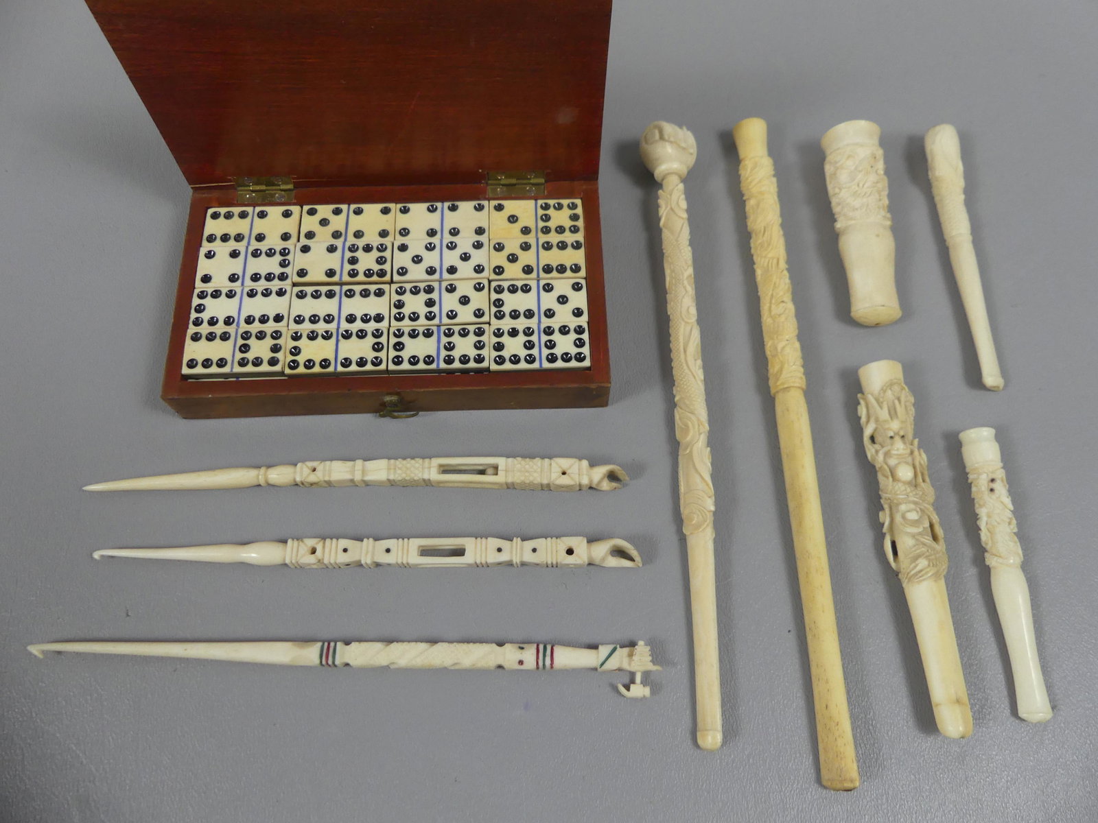 ASSORTED LOT CARVED BONE ITEMS & DOMINOES: Large lot of carved bone items: wood case with miniature domino set, 1.25 in long (case 5.5 x 3); 3 sailor made needles to 7 in long - 2 with fists, one with fist holding hammer; and 6 Japanese items 