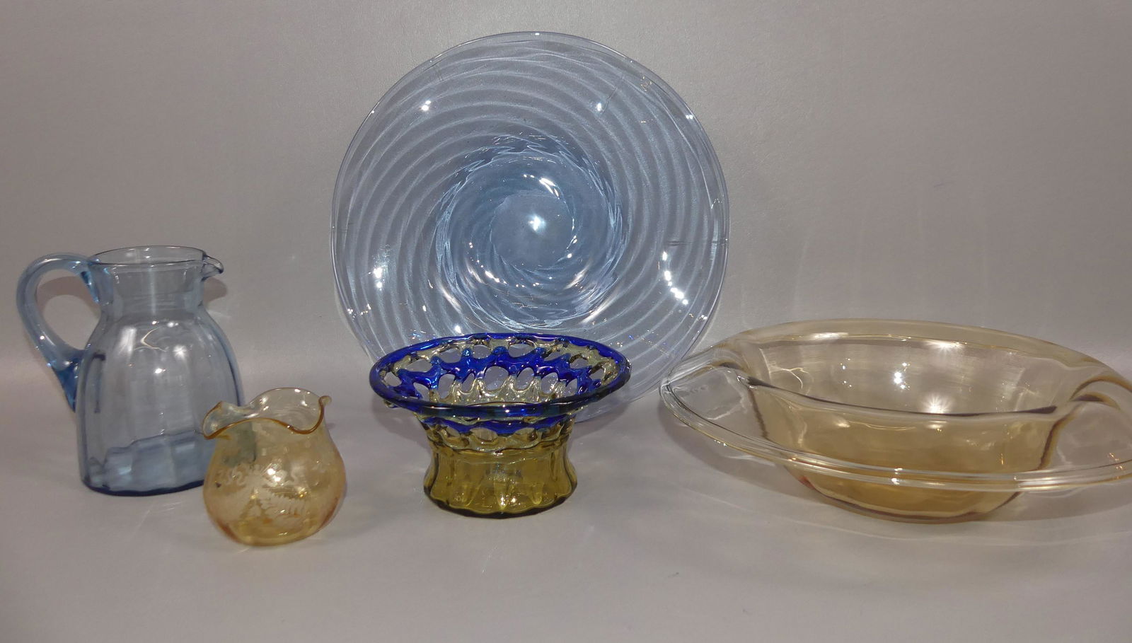 5 PCS STEUBEN BLUE & AMBER ART GLASS: Lot 5 pieces of Steuben glass: 11 in blue swirl bowl; turned lip console bowl; lacy openwork blue and amber bowl, 3 x 6 in; etched small vase; 5.5 in jug. All good condition.
