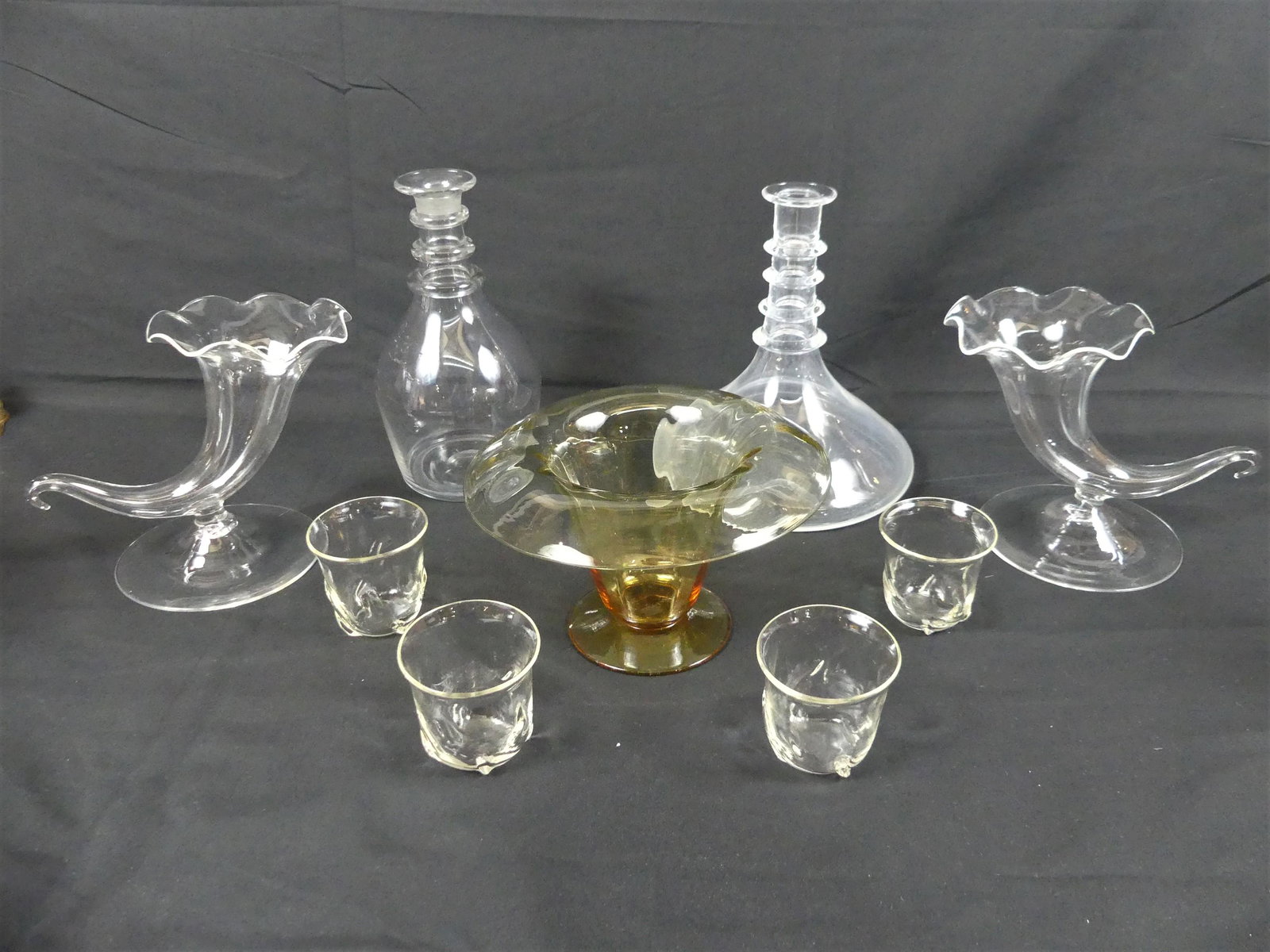 9 PCS ASSORTED STEUBEN GLASS: 9 assorted Steuben colorless crystal items: 2 decanters to 8.5 in (one w/white residue); Pair 6 in cornucopea vases; 4 liquer cups, 2.5 in; and an amber vase with curled liop, 5 x 7.5 inches. All good
