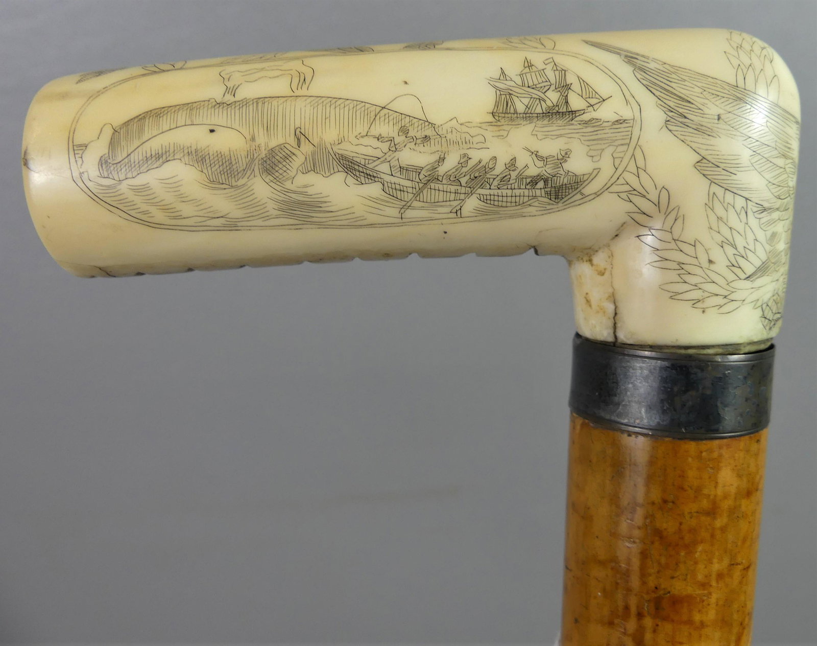 WHALE BONE CANE - WHALING SCENES: 19th century whale bone-handled cane with scrimshaw whaling scenes, eagle, etc. It has a cocabola wood shaft, 32.5 in long, handle 3.75 in. Cracks.