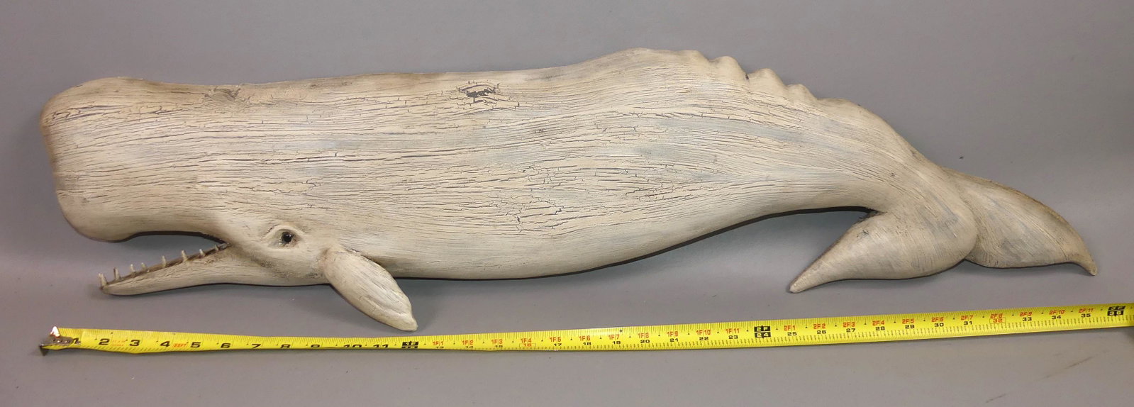 WHALE PLAQUE SIGNED KEN BECKENHAUPT: Large sperm whale hand carved wooden plaque (tail down) signed Ken Beckenhaupt, Cape Cod. White distressed painted finish and glass eye. 38 in long x 9 in high.