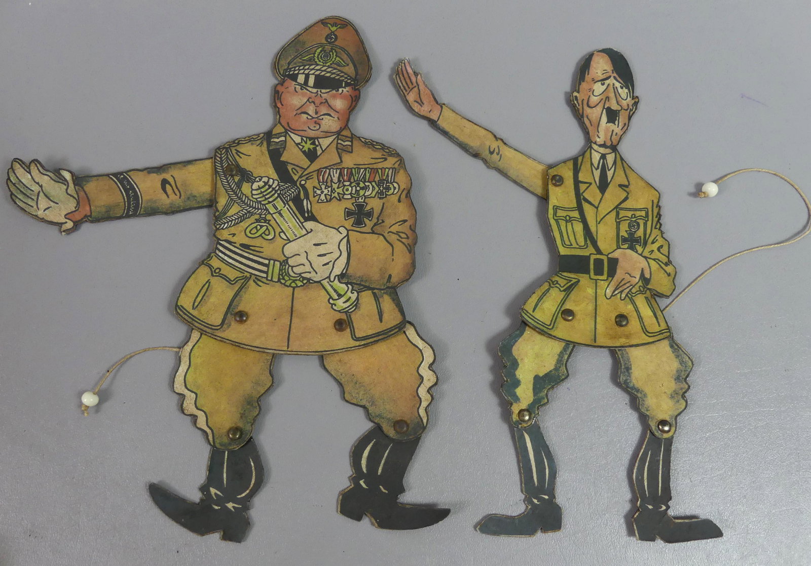 WWII HITLER & GOERING DANCING FIGURES: Two WWII anti-German cardboard lithographed dancing dolls, caricatures depicting Adolf Hitler and the other Hermann Goering. They have pull cords with articulated limbs, signed RJP 130552 on back. Goo